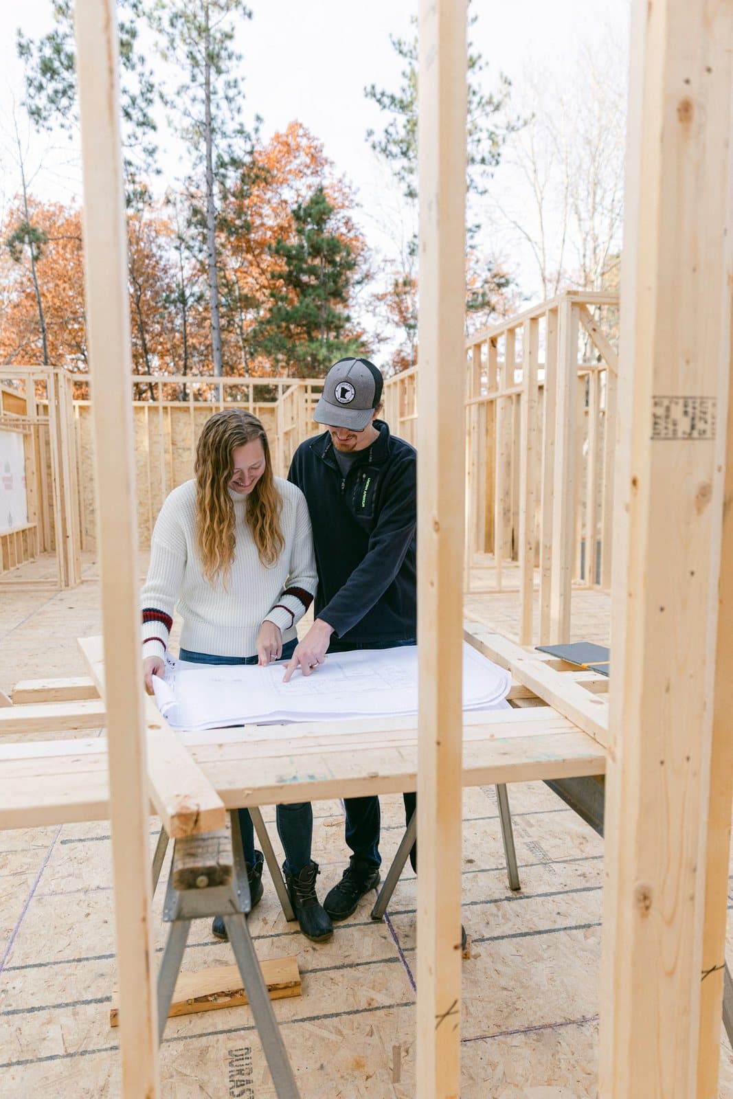 Two people reading building plans inside a new timber frame